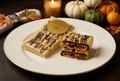 New Sweet Adventure full packaged pumpkin chocolate bar and split pieces showing the filling together on one gold-rimmed Thanksgiving plate