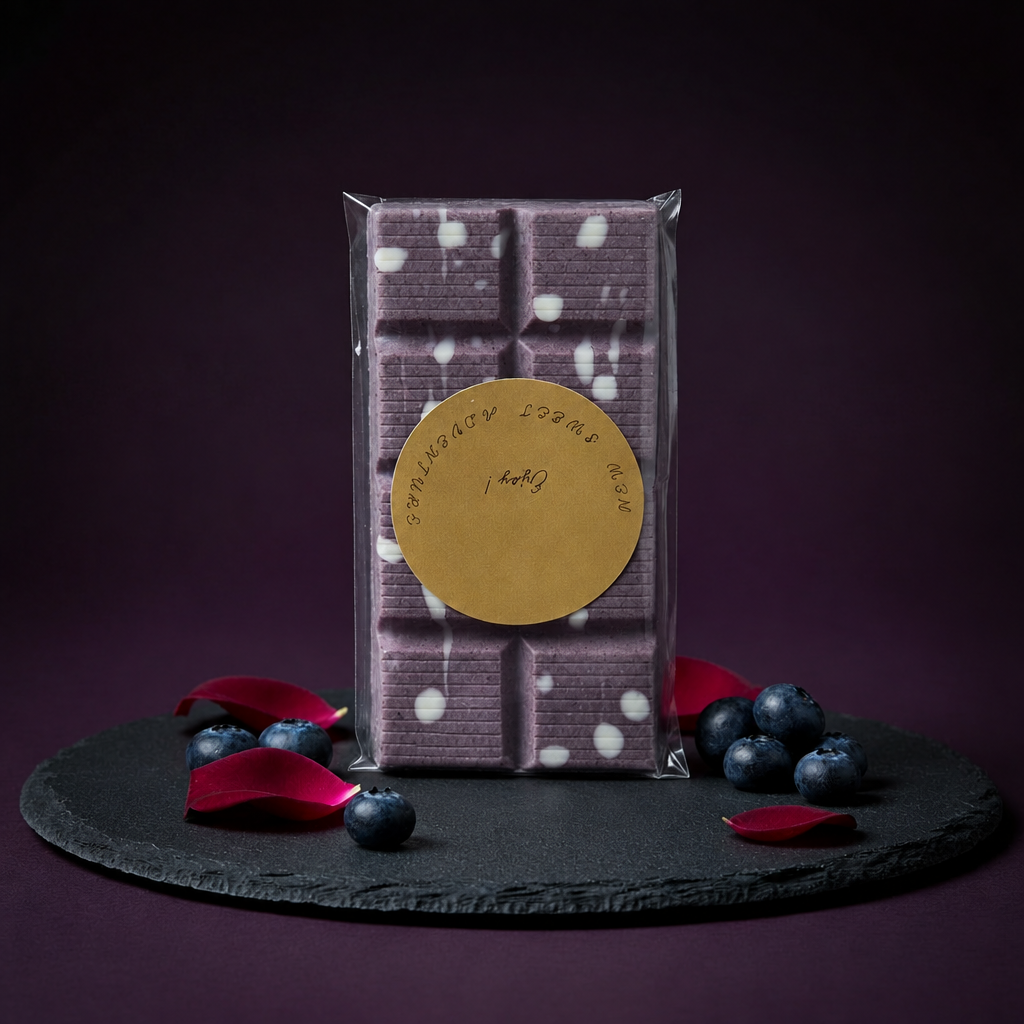 Full packaged organic wild blueberry shell chocolate bar on a dark slate display with blueberries and rose petals.